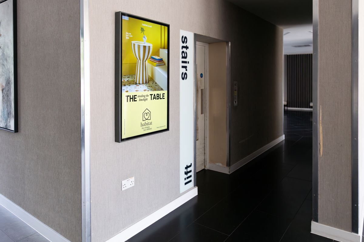A residential corridor hung with framed art, with a portrait Abode screen running a retail offer.