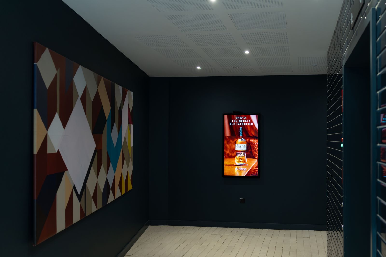 A navy lobby with a bold geometric mural and a single glowing portrait Abode screen.